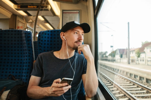 Guy on a train listing to a podcast