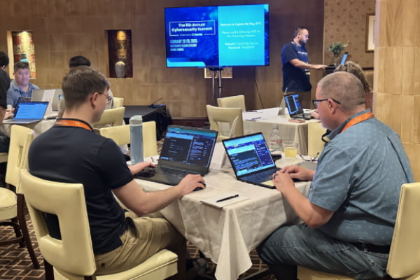 Participants on laptops working on a TribalHub cybersecurity challenge